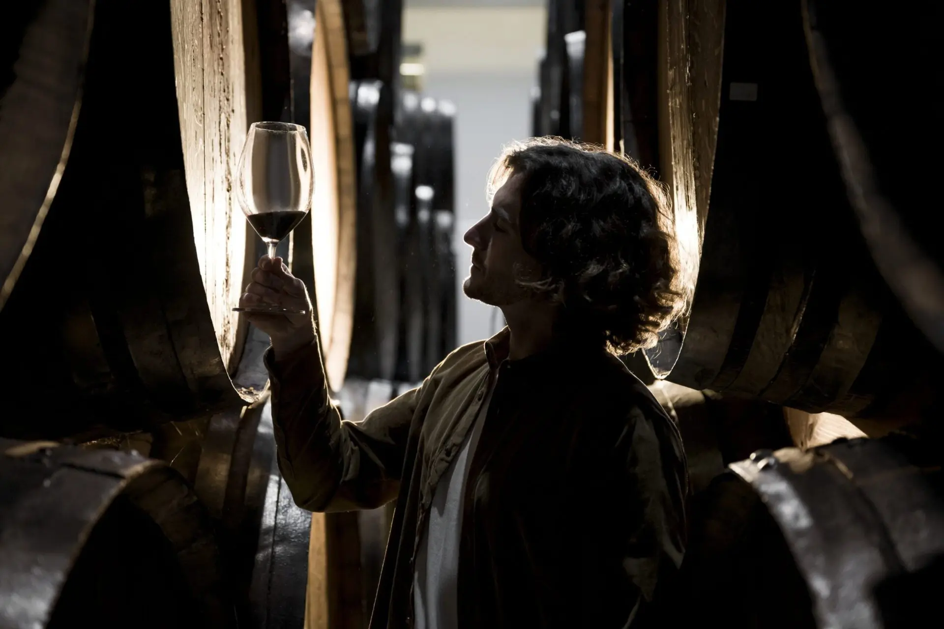 femme qui tient un verre de vin a cote de cuves